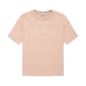 A Fear of God Essentials T-shirt in a soft pink color on a hanger.